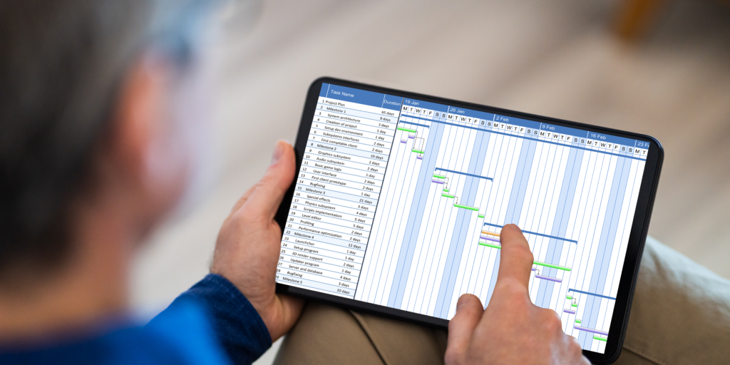 a picture of a person operating a Gantt chart on a tablet.  The person is clicking on features of the Gantt chart.